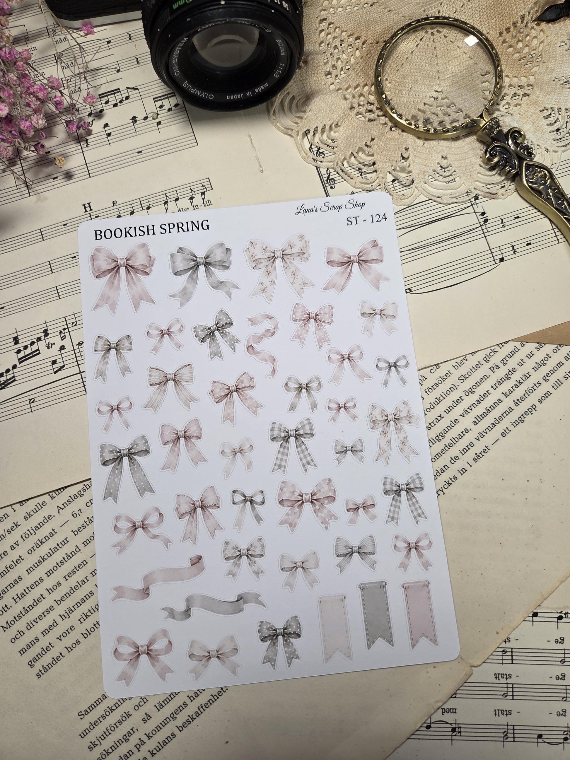A sticker sheet with assorted bows in pastel pink, grey, and white. The bows have polka dots, gingham, and plain designs. The text "BOOKISH SPRING" is printed on the sheet.