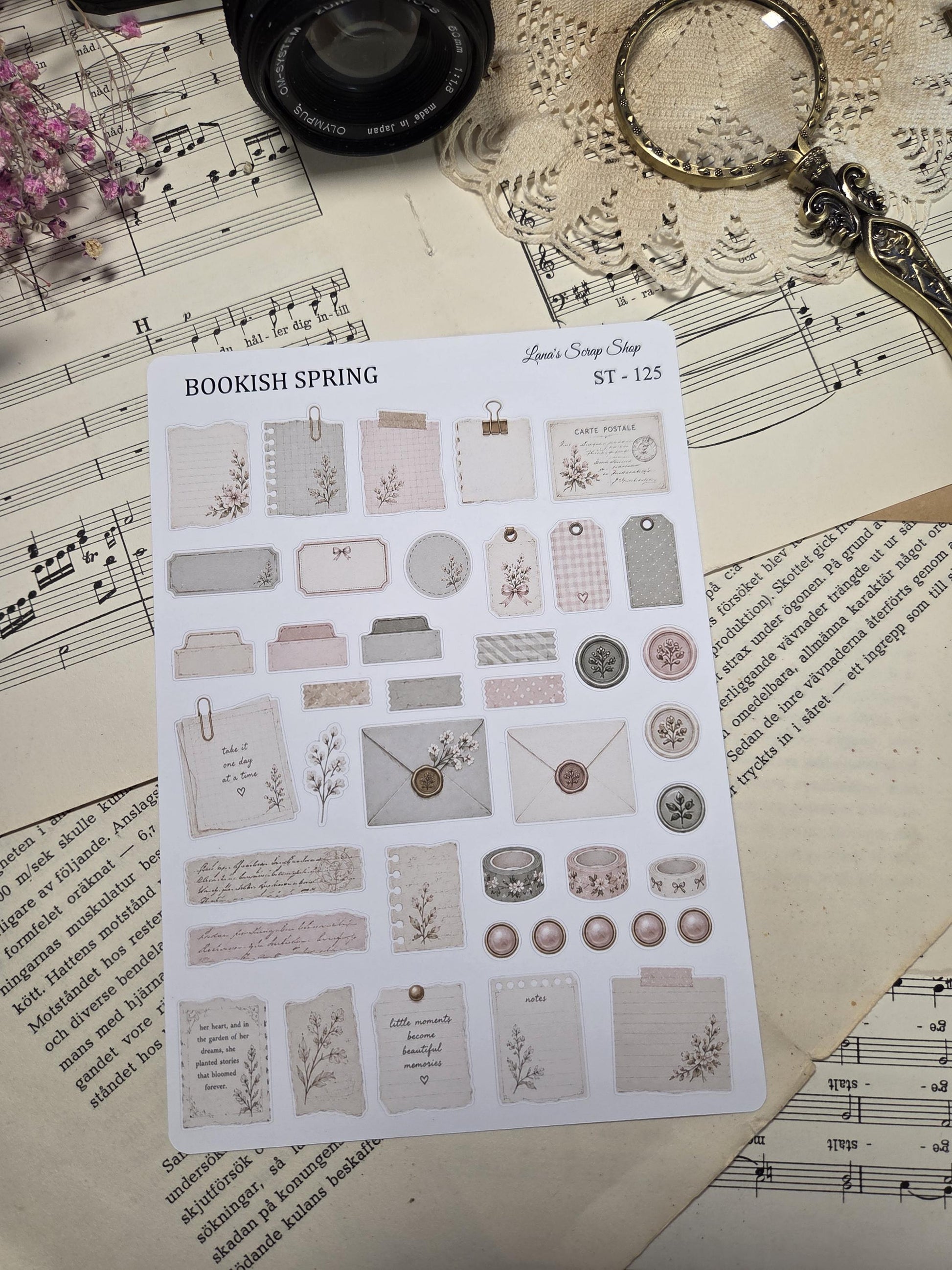 A sticker sheet of decorative stickers with a 'Bookish Spring' theme. The stickers feature floral designs, tags, labels, washi tape, and envelopes in soft pink, beige, and grey tones. Includes the text "Bookish Spring" and "ST-125".